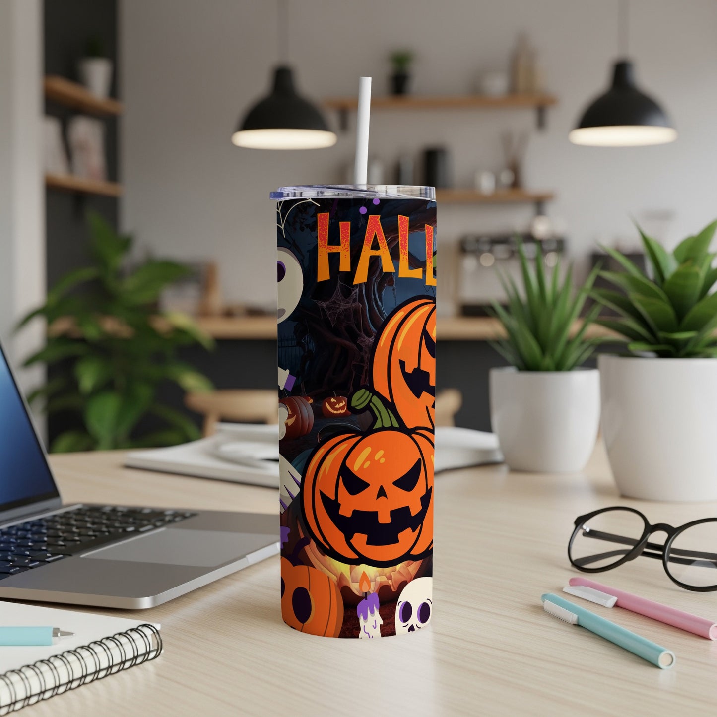 Halloween tumbler with pumpkins, skulls, and the word "Halloween" on a desk.