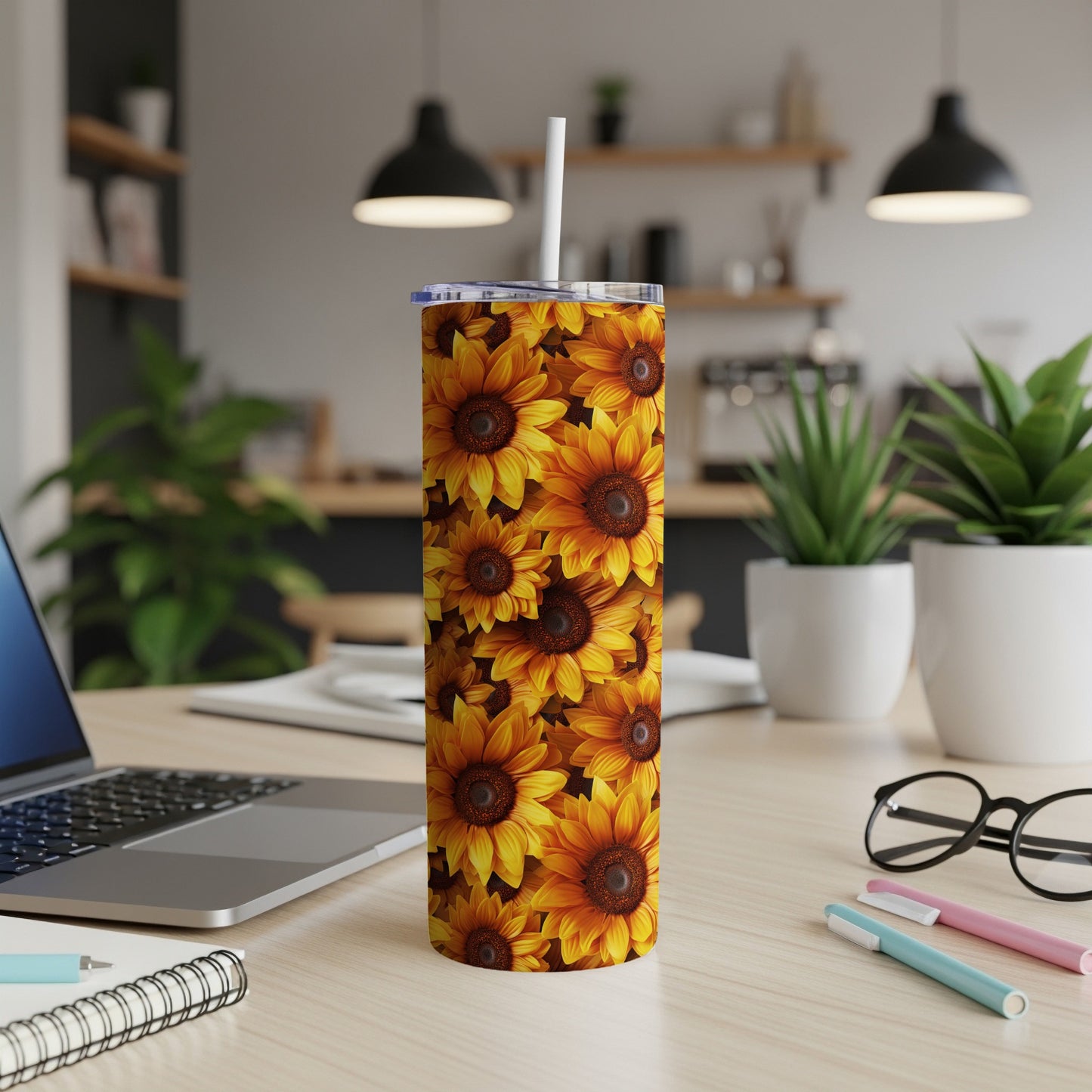 Sunflower print skinny tumbler with straw on desk.