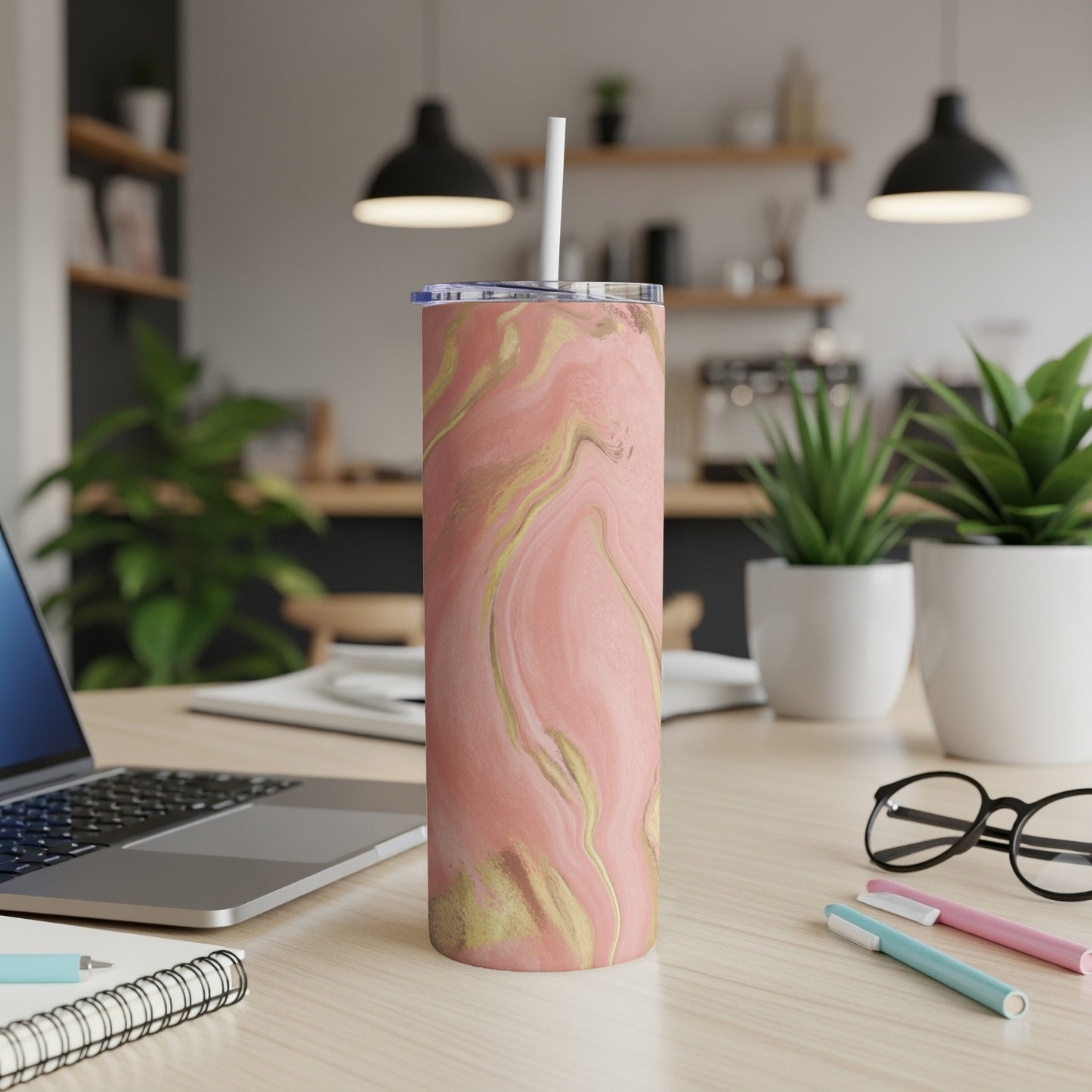 Pink and gold marbled tumbler with straw on a desk.