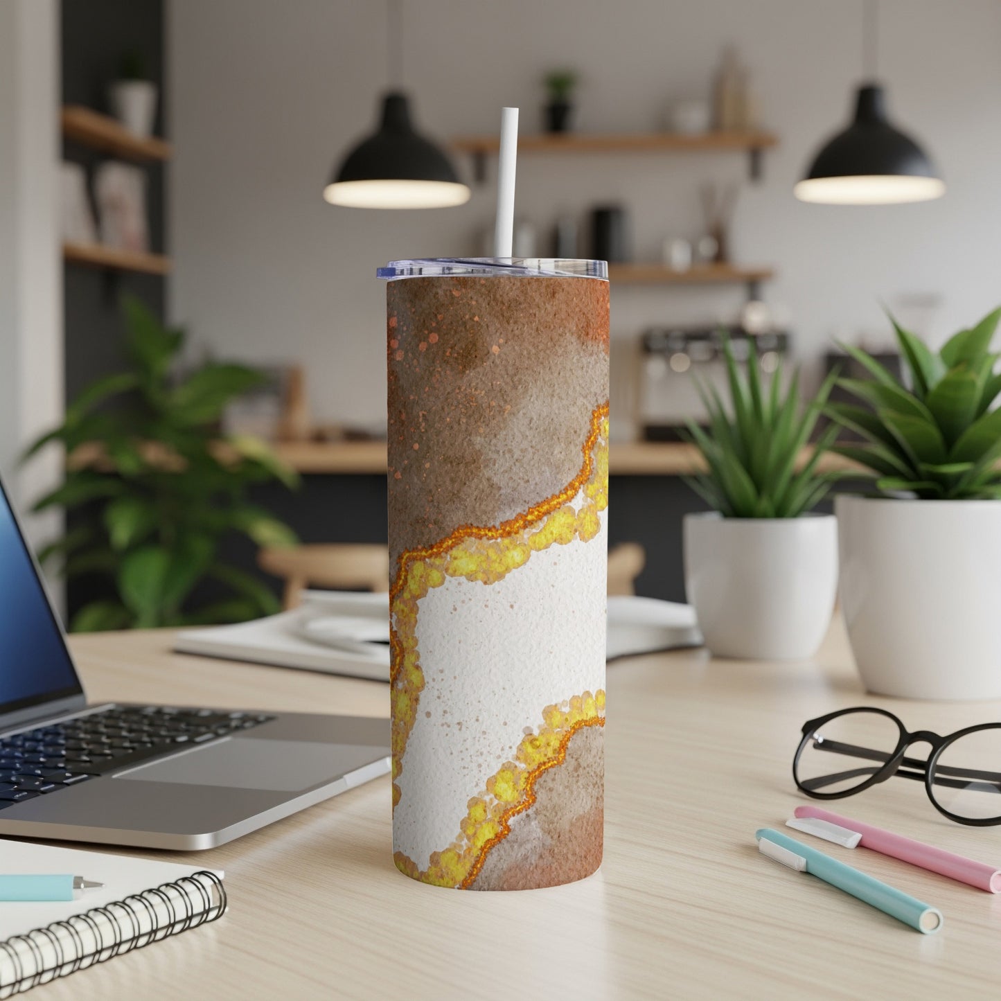 Tumbler with white and brown marbled design with gold accents, on a desk.