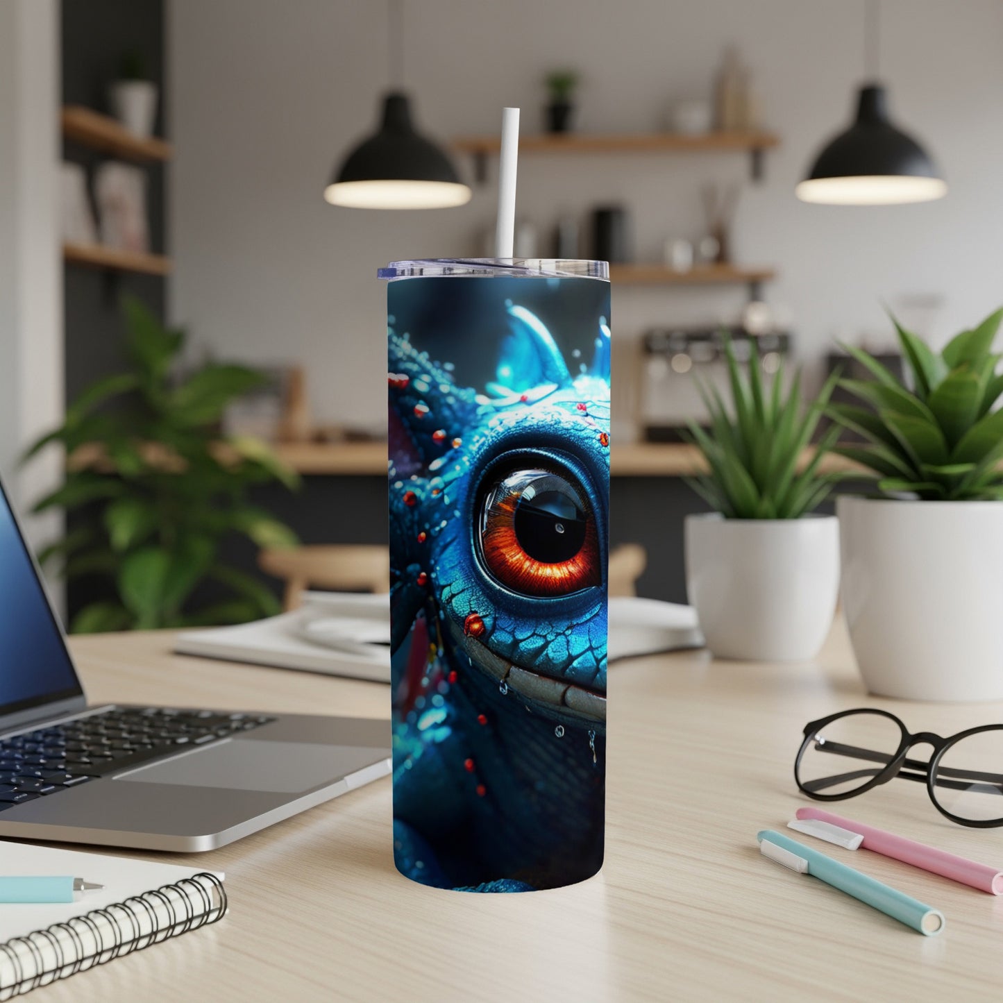 Blue dragon tumbler with large orange eye, on a desk.