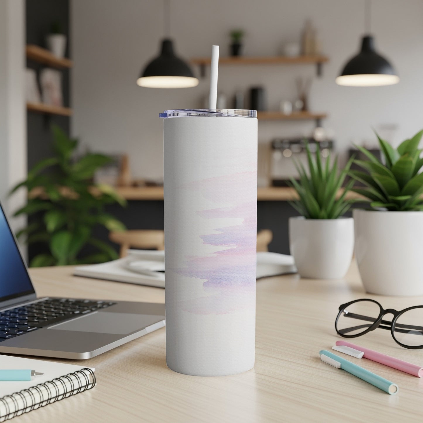 White tumbler with pastel watercolor wash design on a desk.