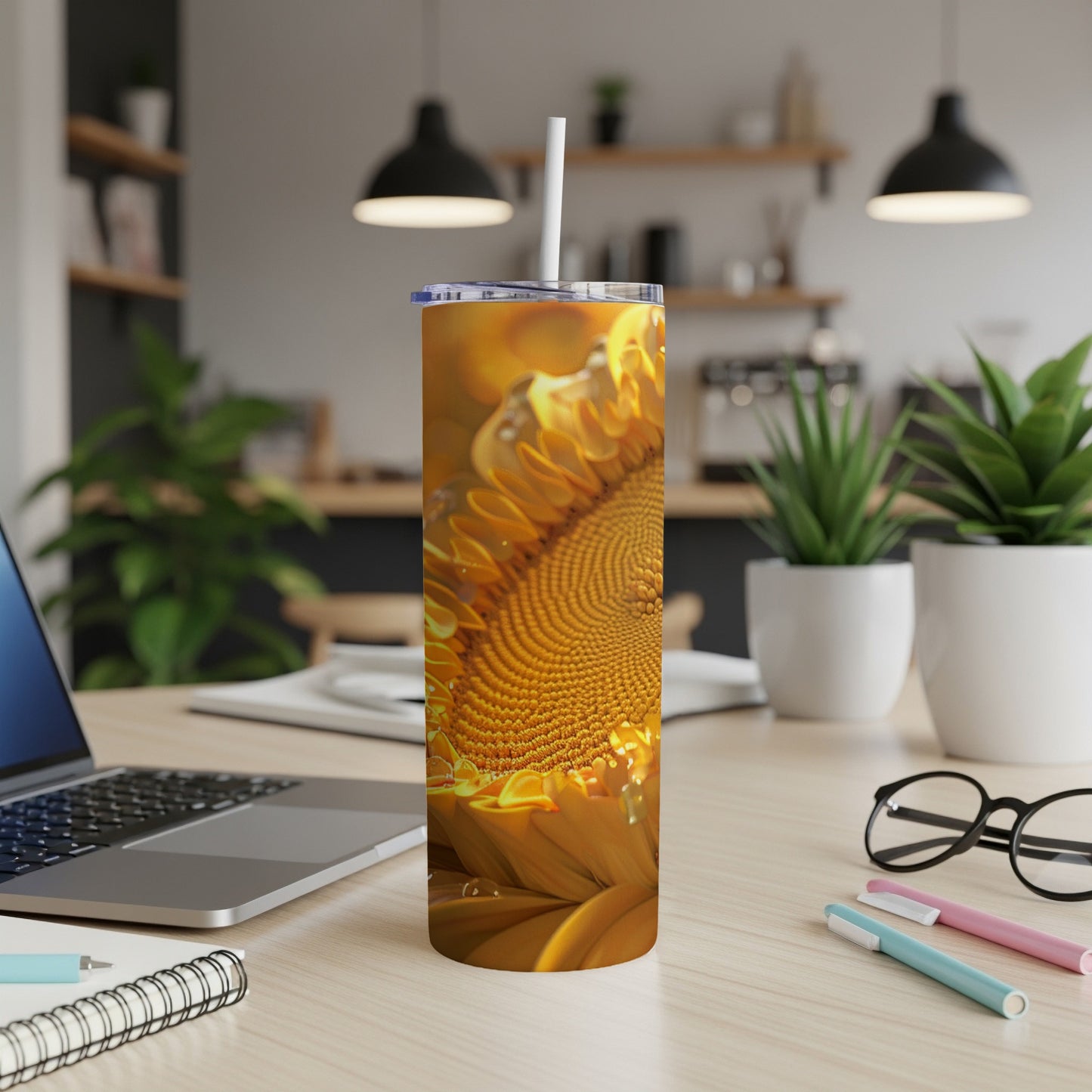 Sunflower pattern on a tumbler with a straw, on a desk with a laptop.