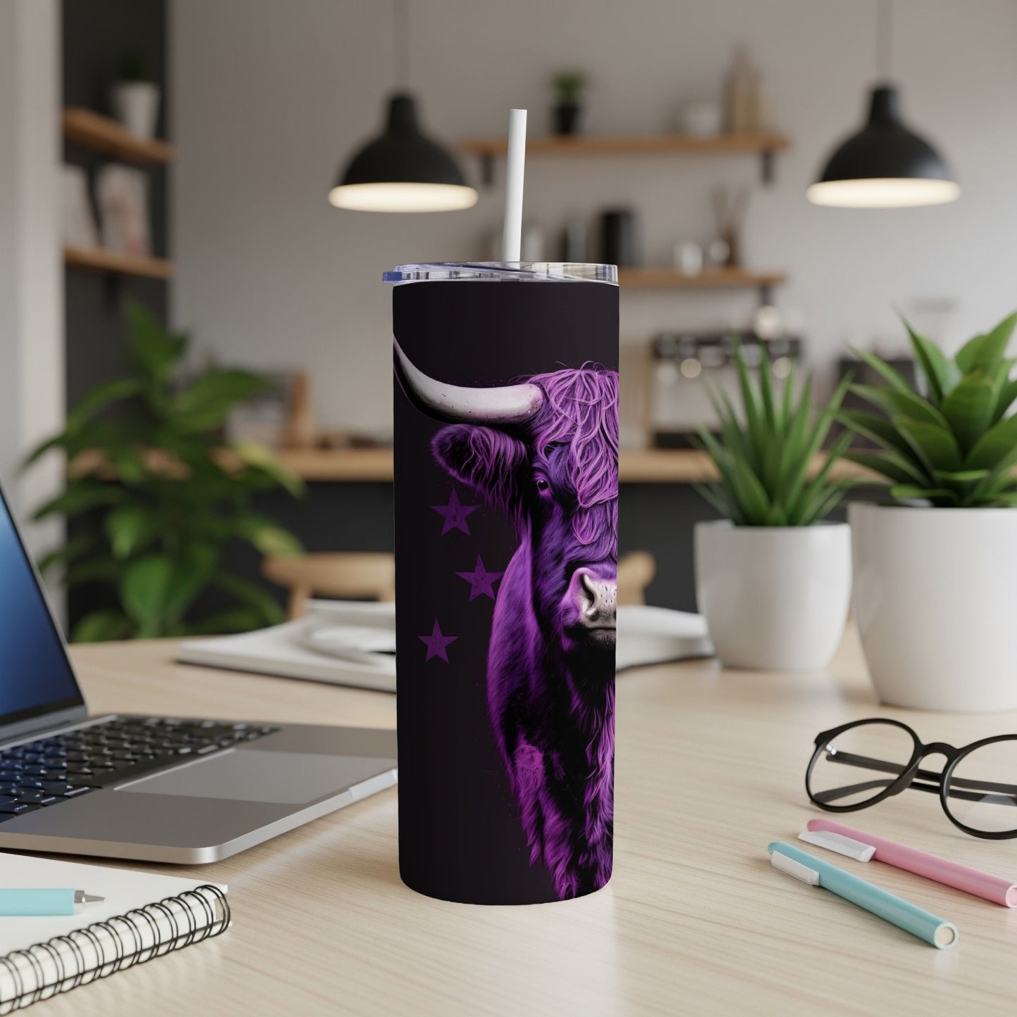 Purple Highland cow design on a dark tumbler with straw, on a desk.