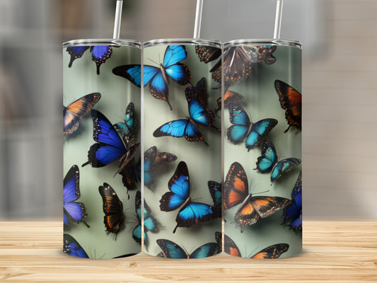 Three tumblers with blue and orange butterflies on a blurred background.