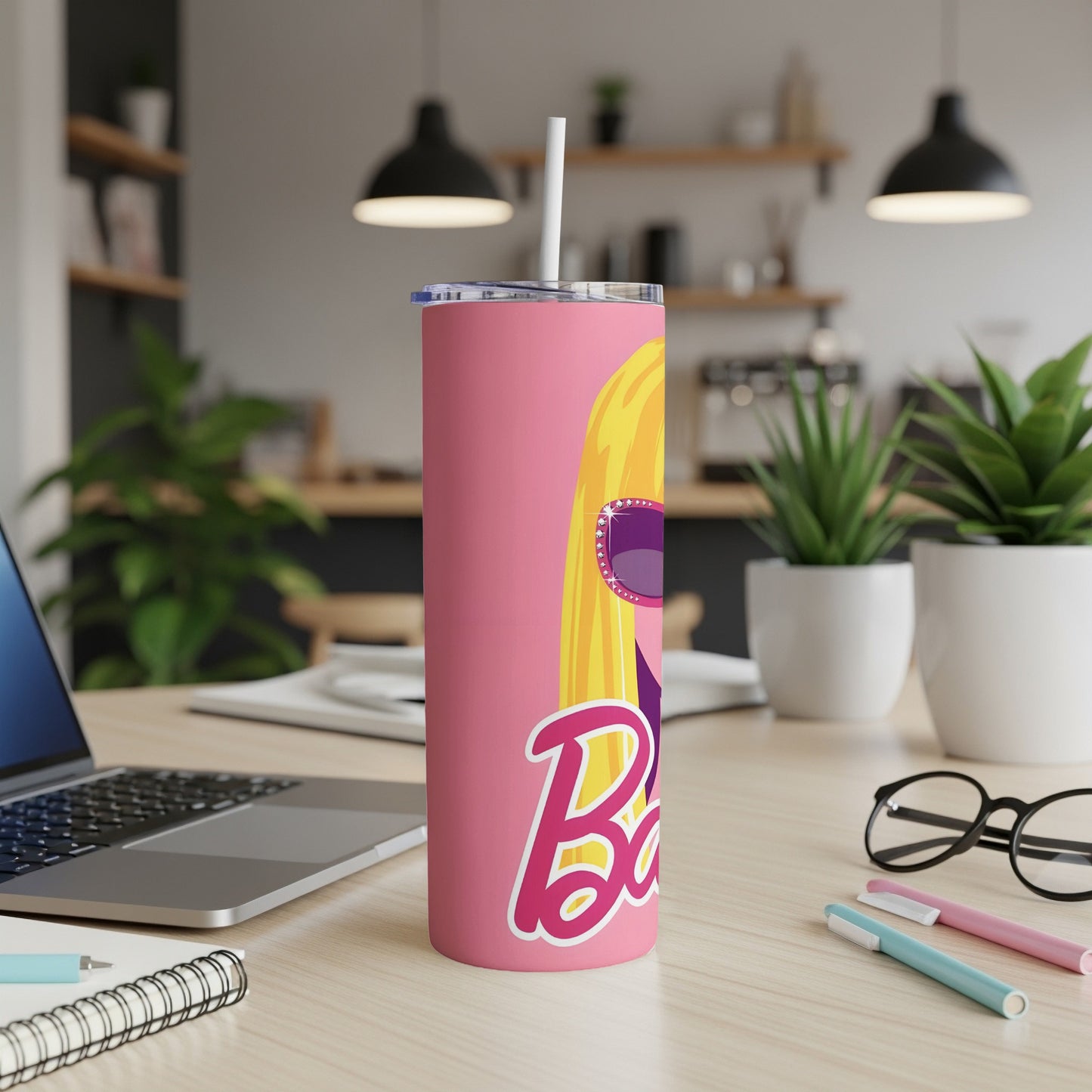 Pink Barbie tumbler with blonde hair and sunglasses on a desk.