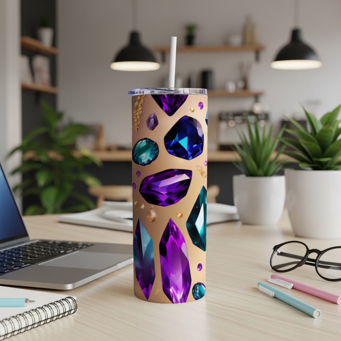 Tumbler adorned with various colorful, faceted gemstones on a desk.
