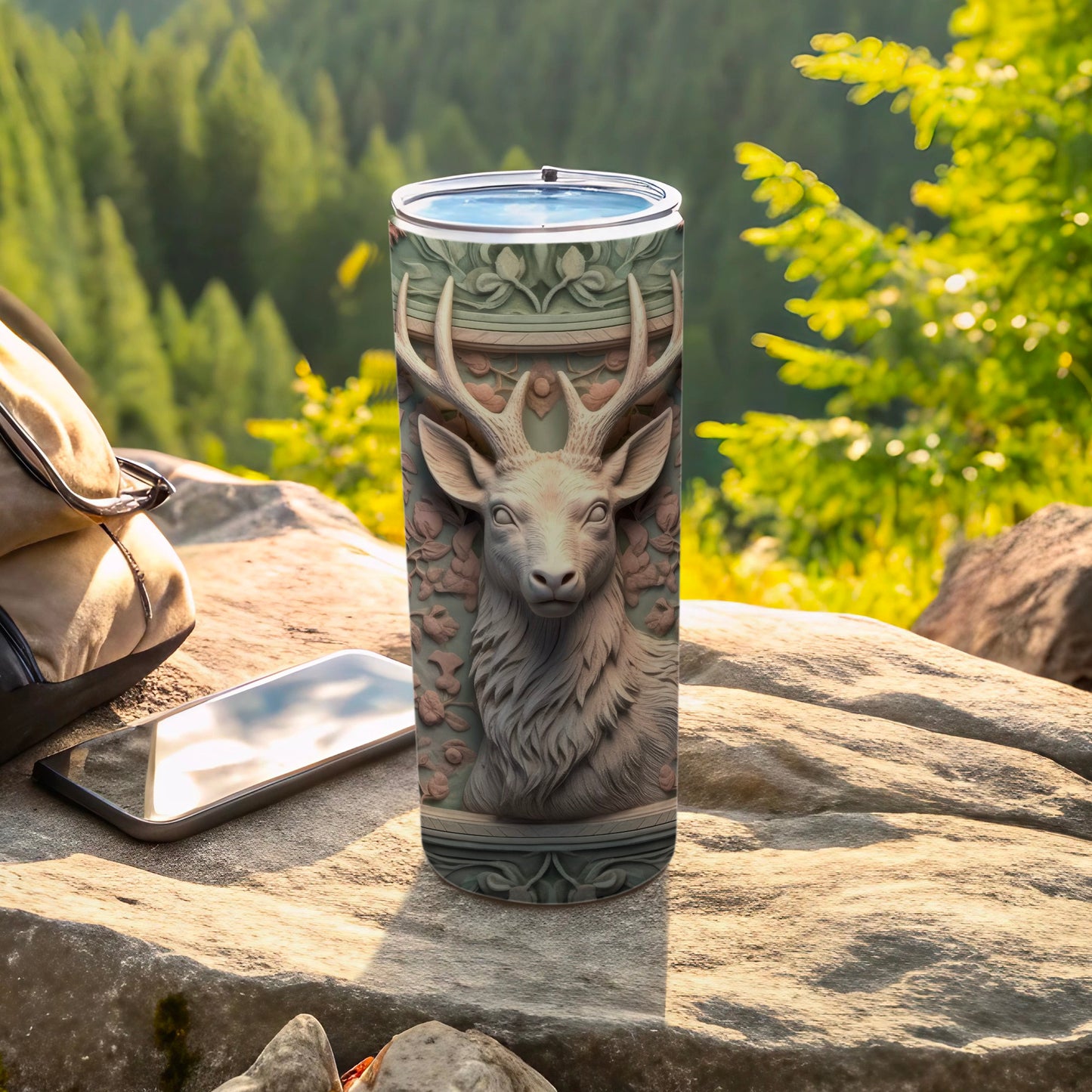 Deer head design on a tall, narrow tumbler on a rocky surface.