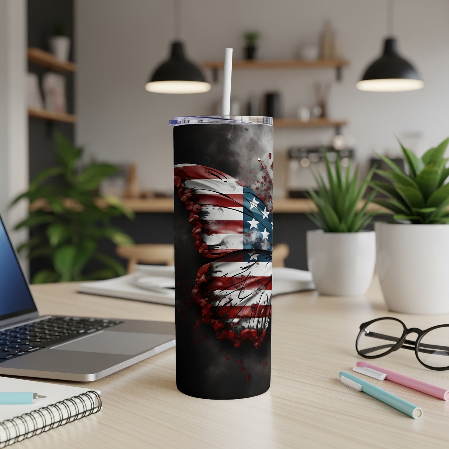 Tumbler with American flag butterfly design, straw in lid, on a desk.