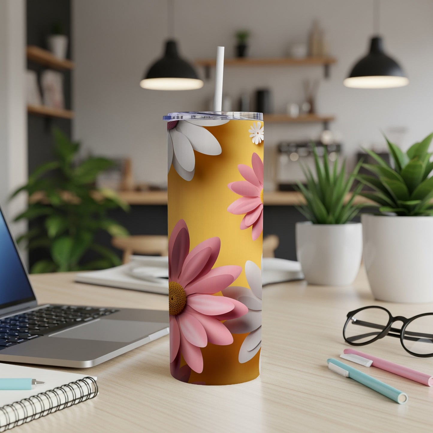 Tall yellow tumbler with pink and white daisies and a straw.
