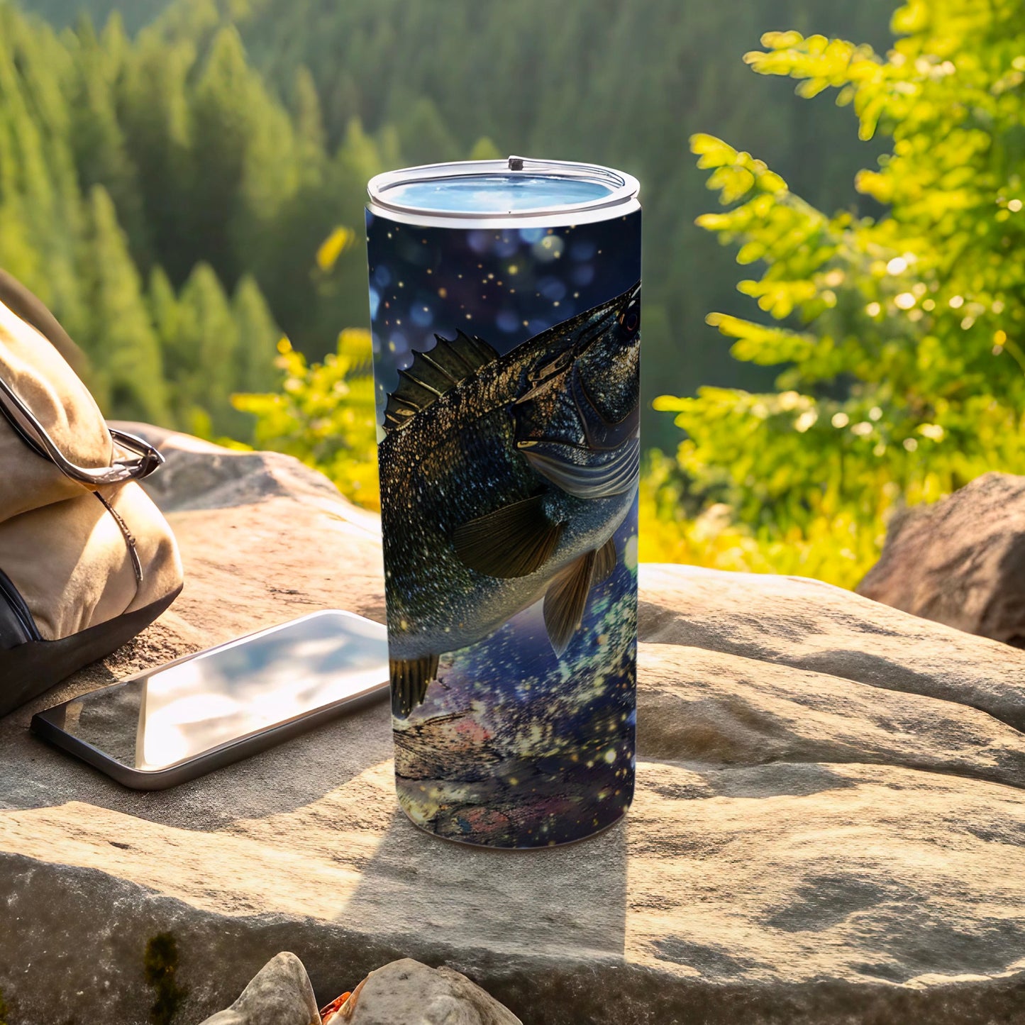 Tumbling fish design on a stainless steel tumbler, resting on rocks.