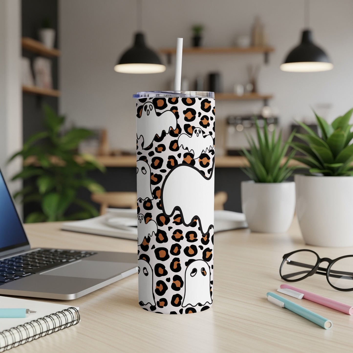 White tumbler with leopard print and cartoon ghosts, featuring a straw.