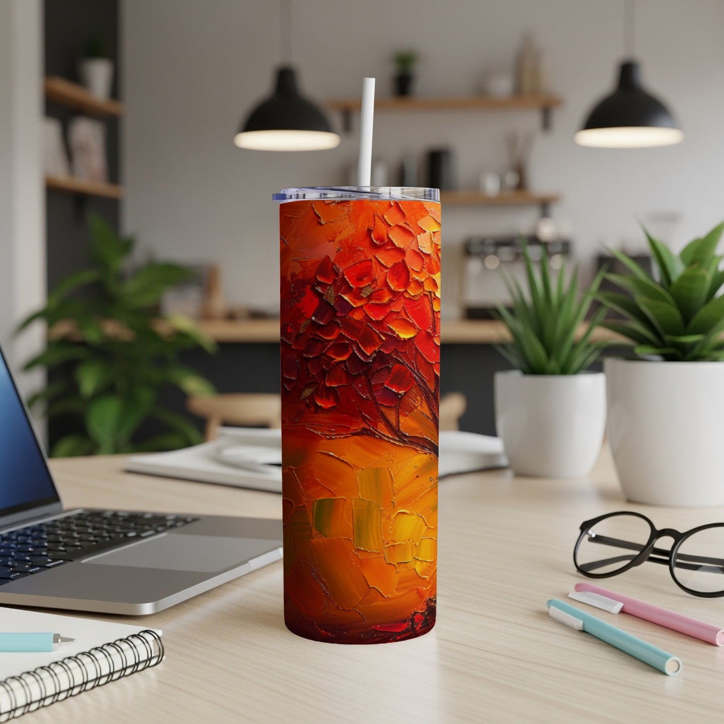 Tall, skinny tumbler with a vibrant abstract red and orange textured design, on a desk.