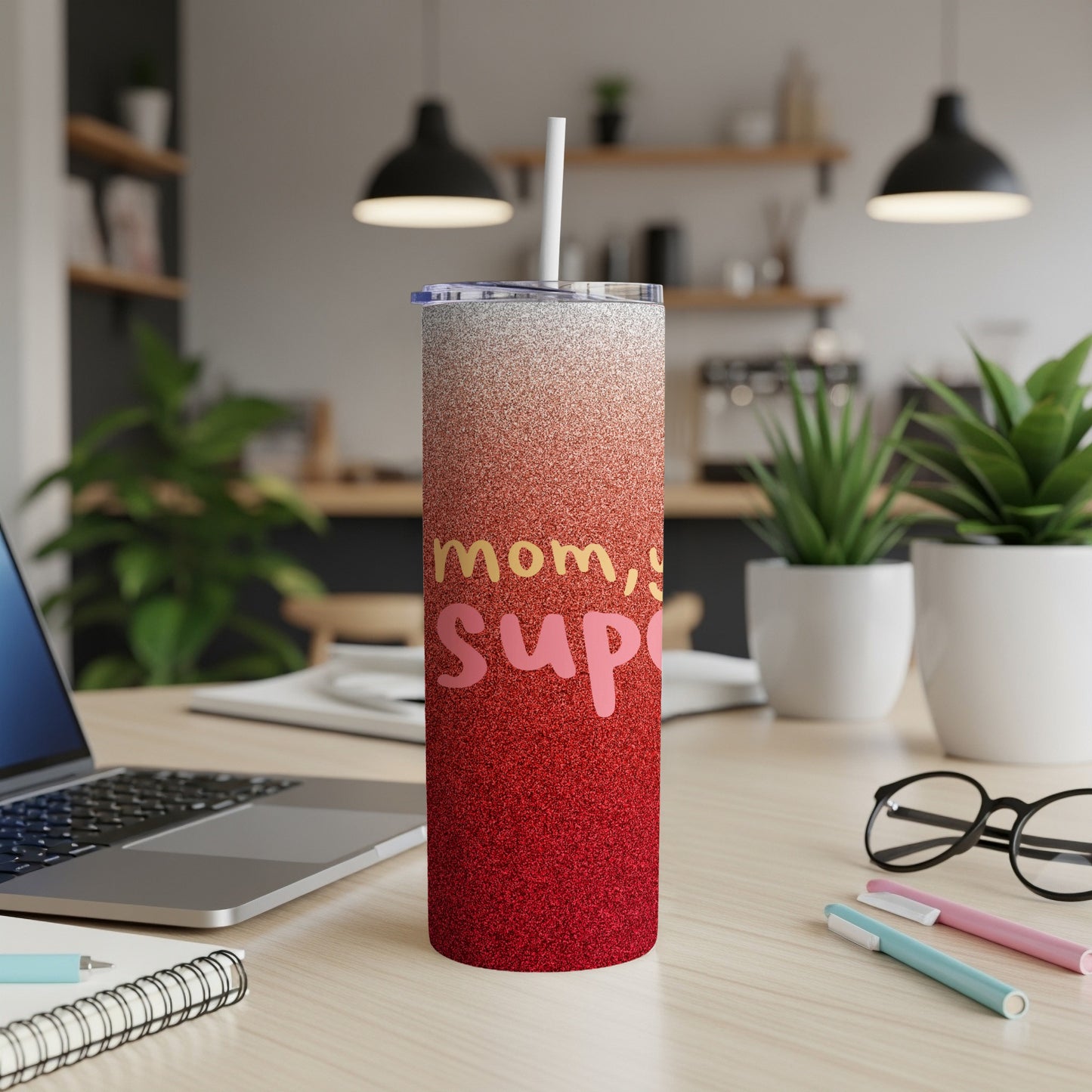 Red and pink glitter tumbler with "Mom, Super" text and straw on a desk.