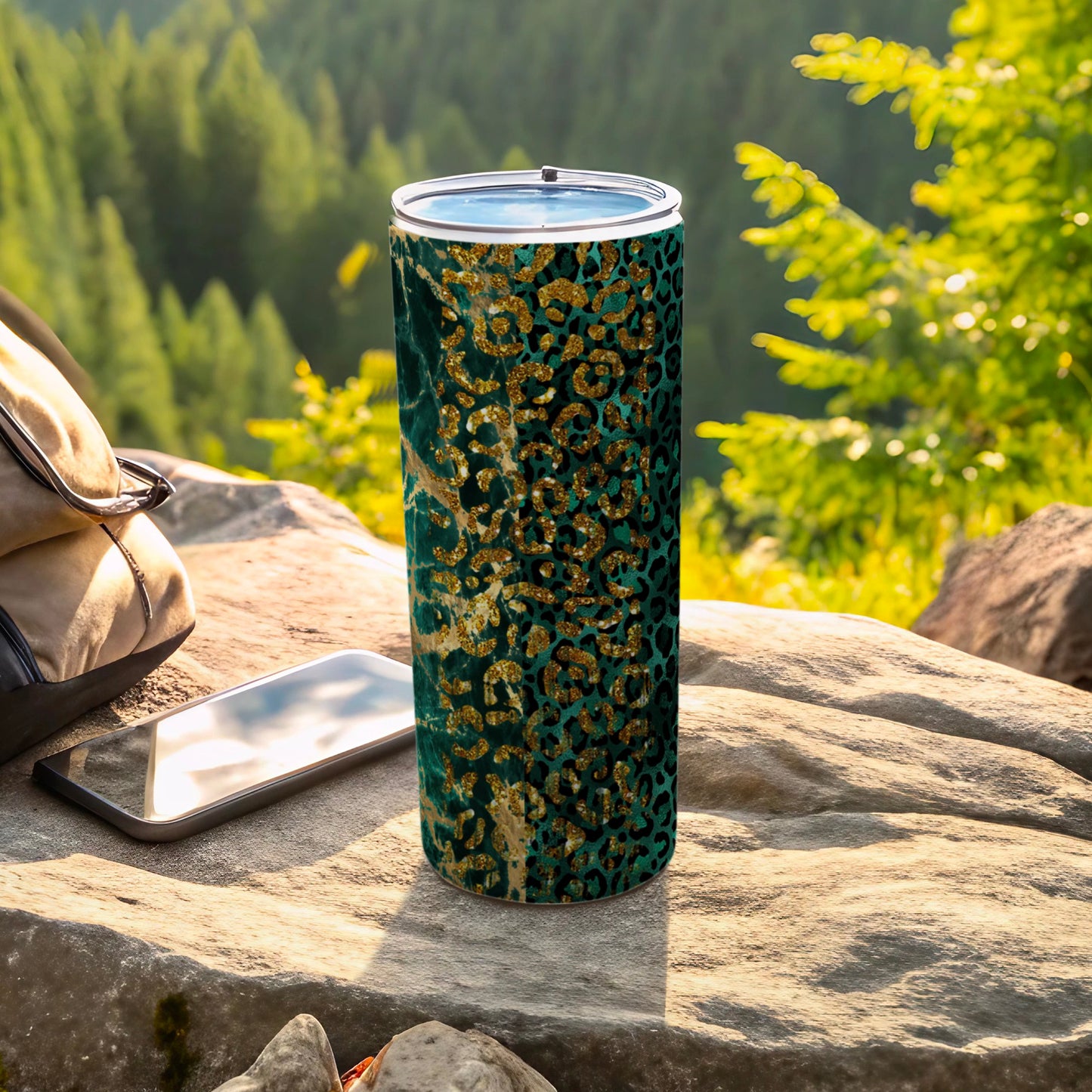 Green tumbler with gold leopard print pattern on a rocky outdoor surface.