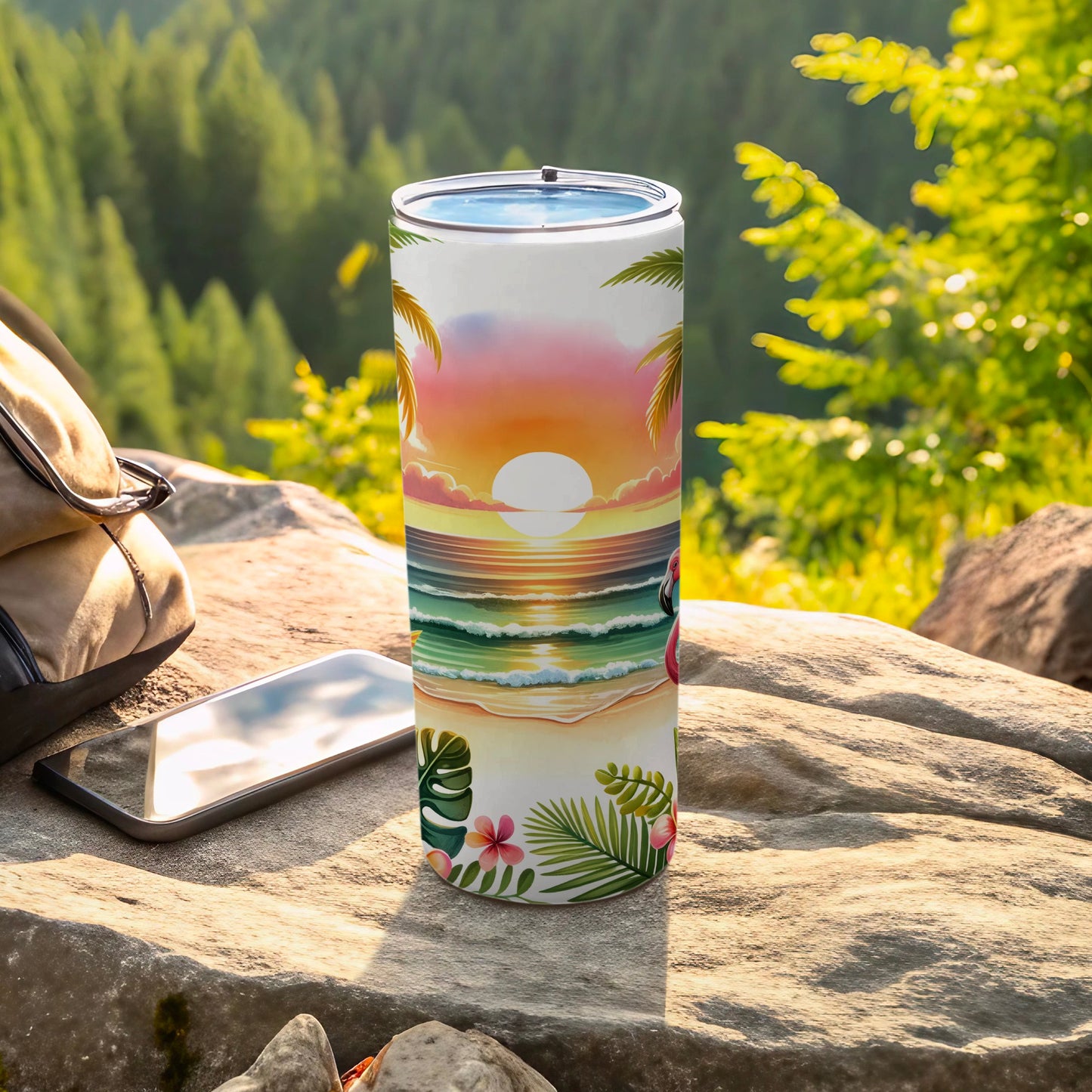 Tumbler with tropical sunset beach scene and flamingo, next to phone and backpack.
