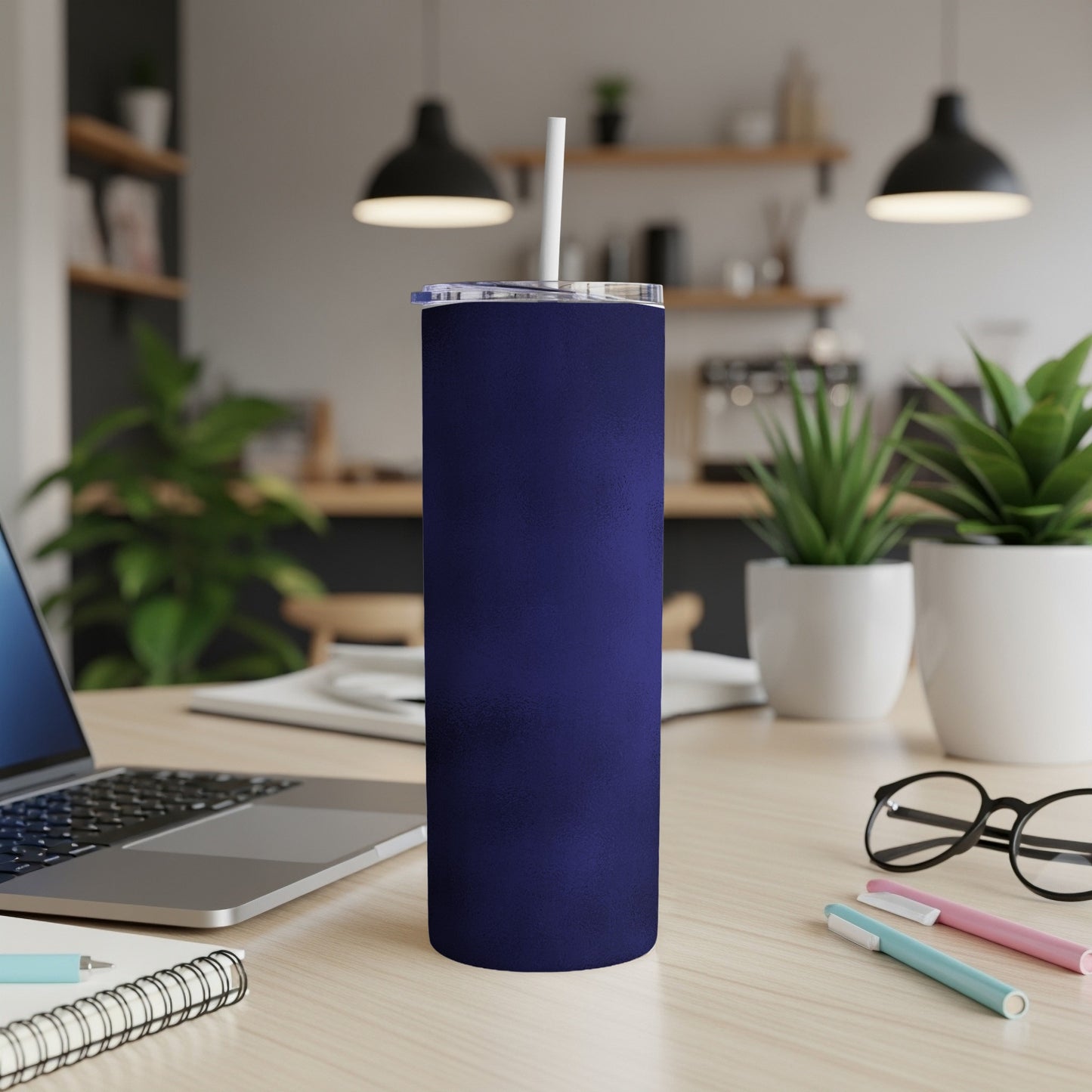 Dark navy blue tumbler with a white straw on a wooden desk.