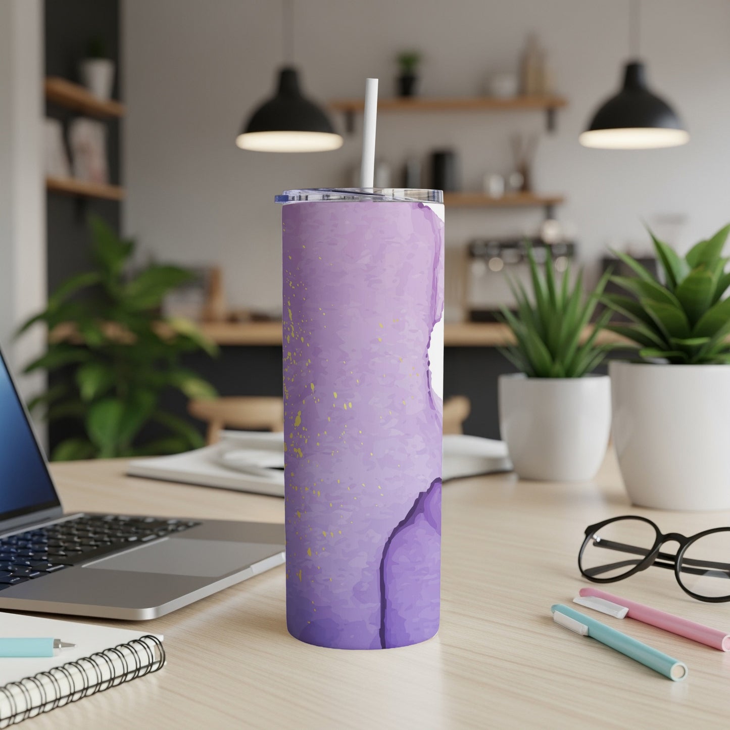 Purple watercolor tumbler with gold flecks and a white straw on a desk.