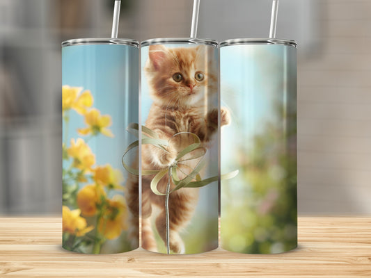 Ginger kitten playing with a green ribbon on a floral background.
