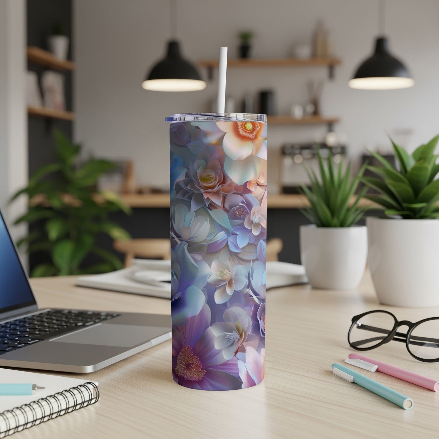 Tall floral tumbler with straw on desk next to laptop.