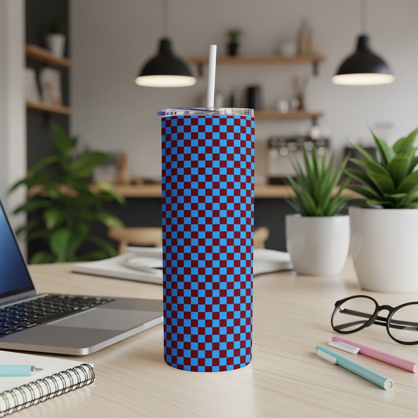 Maroon and blue checkered tumbler with white straw on a desk.