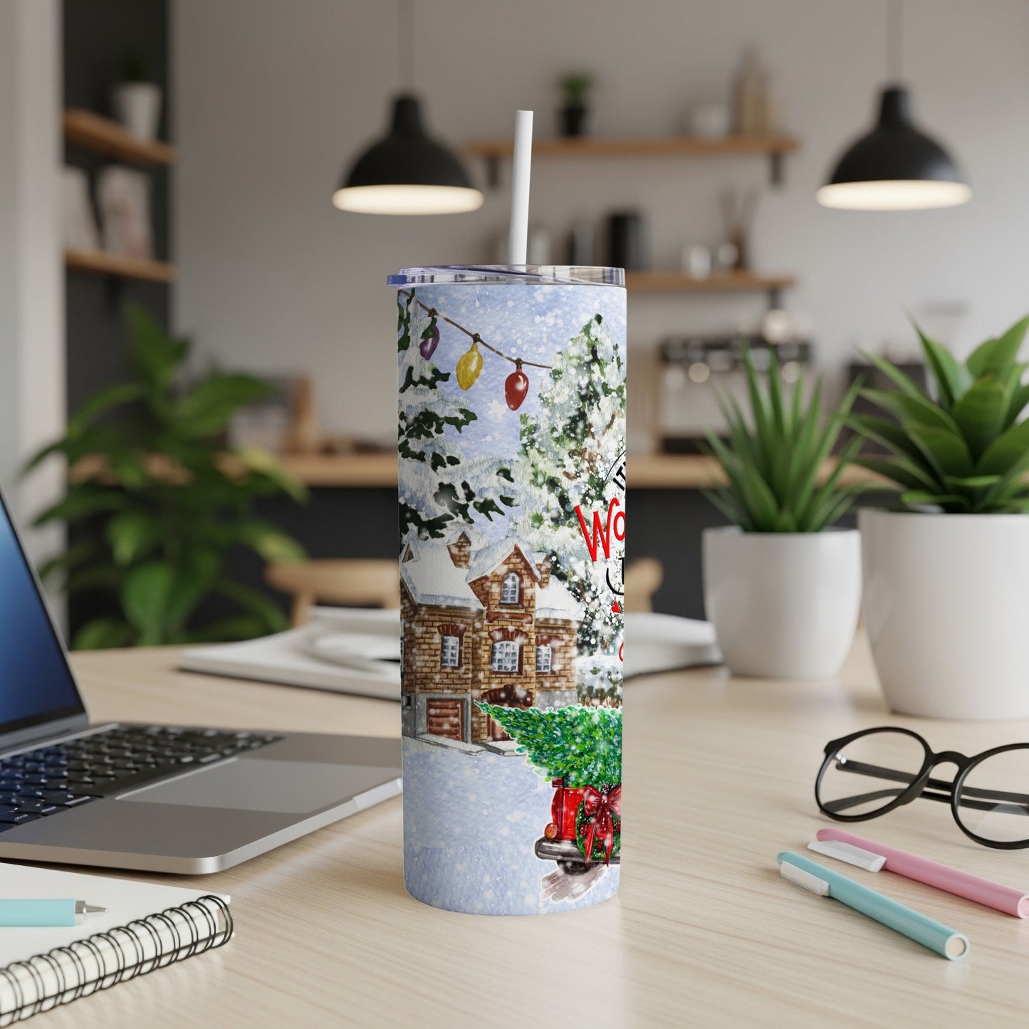 Winter scene tumbler with decorated tree and festive truck, on desk.