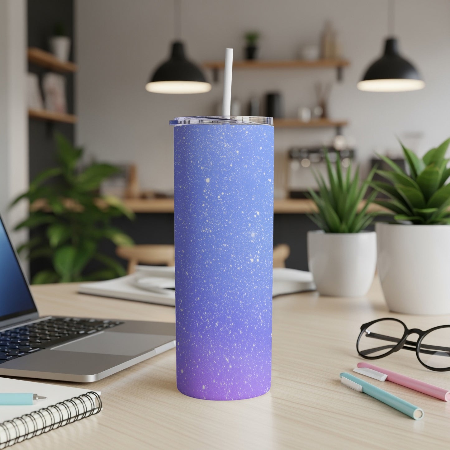 Gradient purple and blue speckled tumbler with white straw on desk.