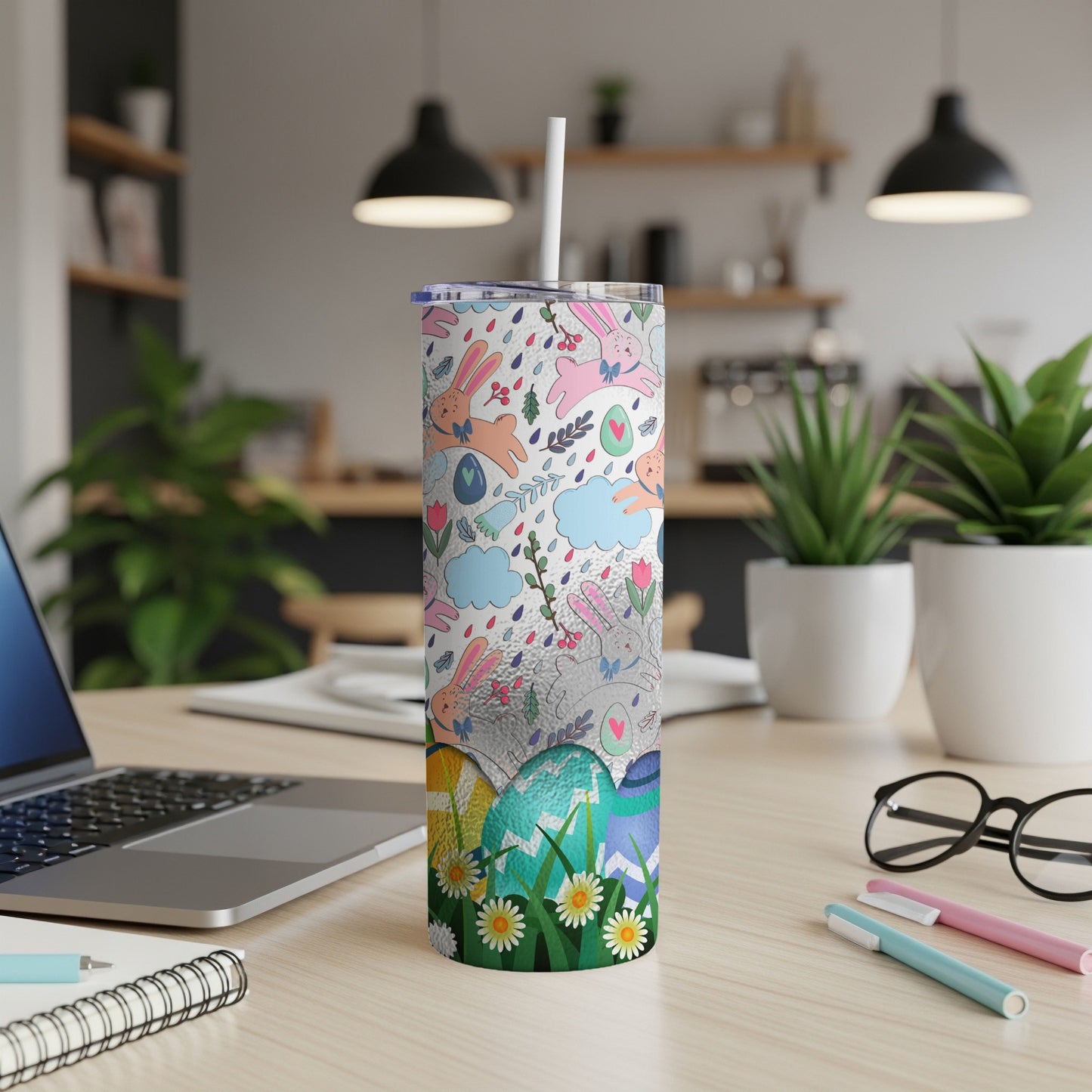 Easter themed tumbler with rabbits, eggs, and clouds on a desk.