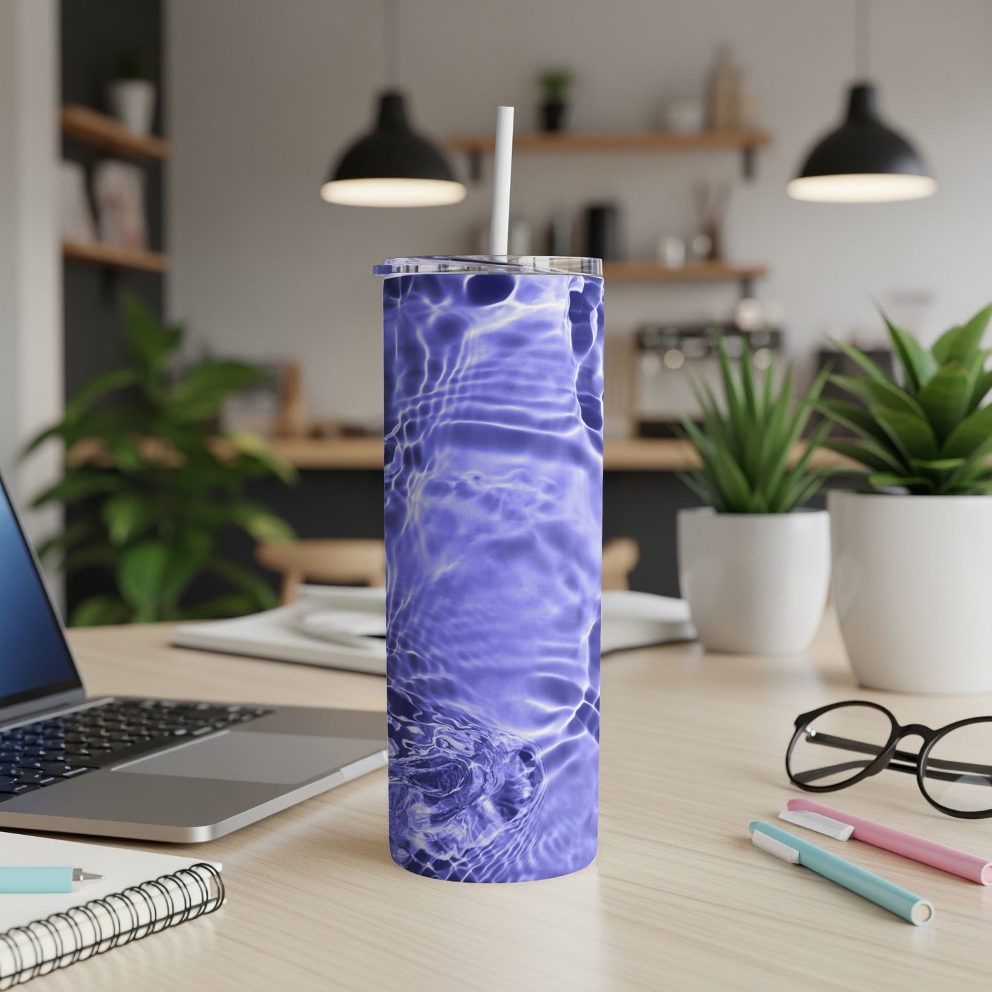 Blue ripple pattern on a stainless steel tumbler with a straw, on a desk.