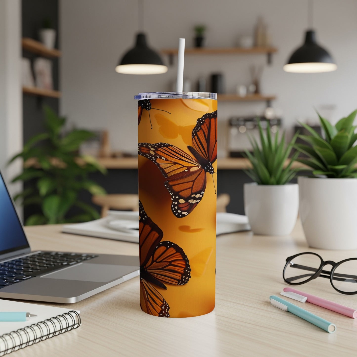Monarch butterflies on a yellow tumbler with a straw in a kitchen setting.