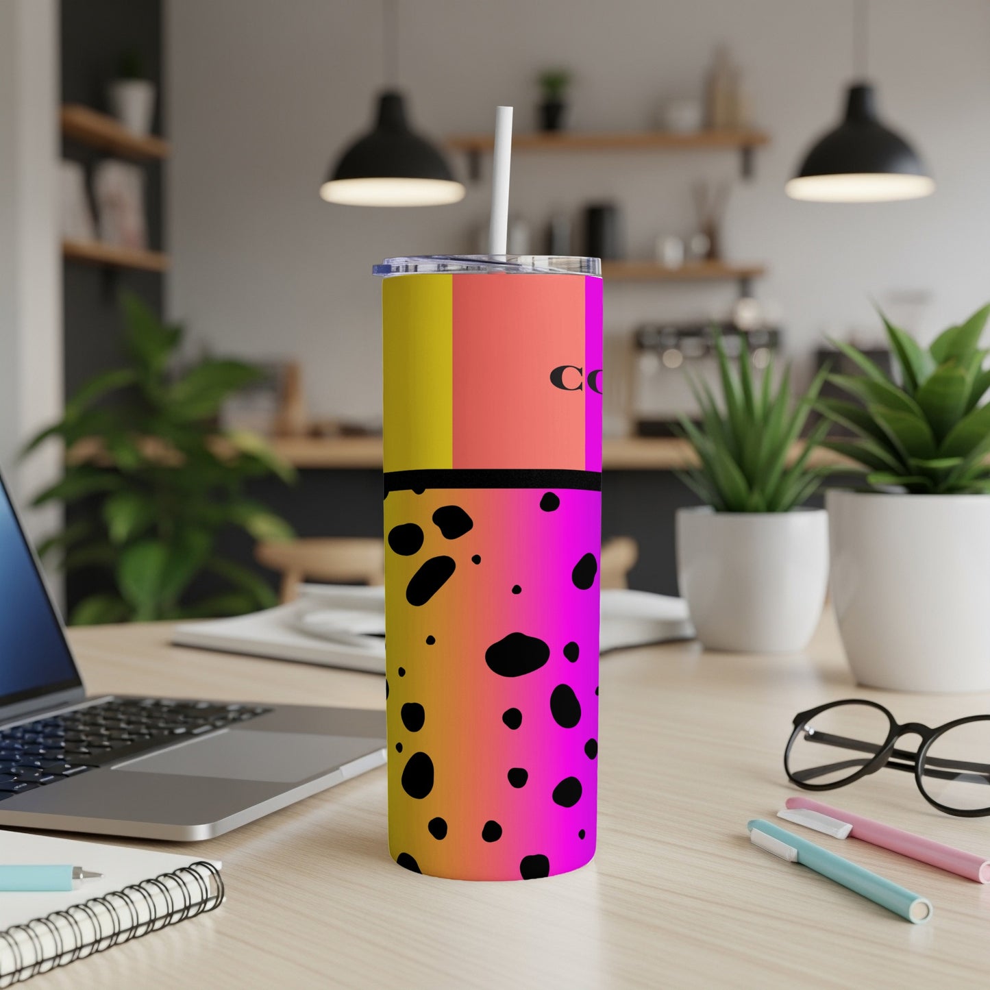 Gradient tumbler with black spots and text "COF" on a desk.