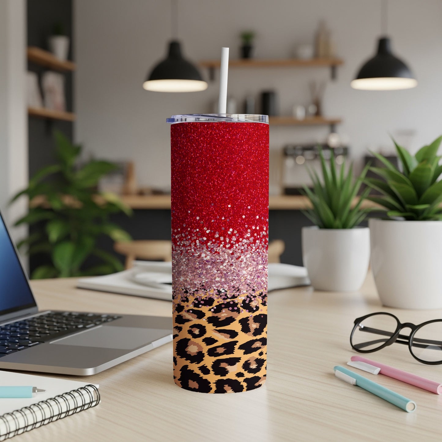 Red glitter tumbler with leopard print accent and straw on desk.