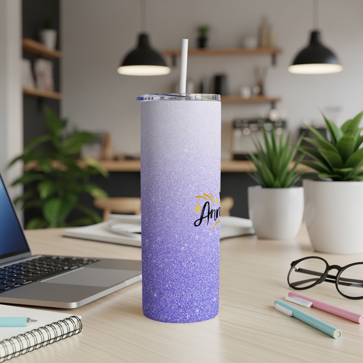 Sparkling purple tumbler with a straw and text, on a desk.