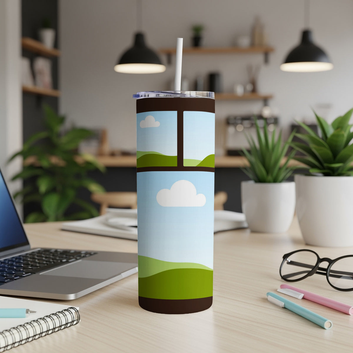 Tumbler with landscape art, clouds, and rolling green hills on a desk.