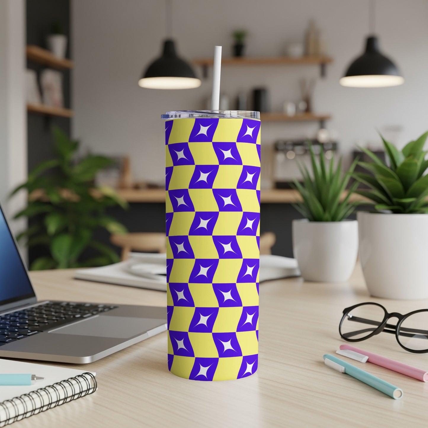 Purple and yellow geometric tumbler with straw on a desk.