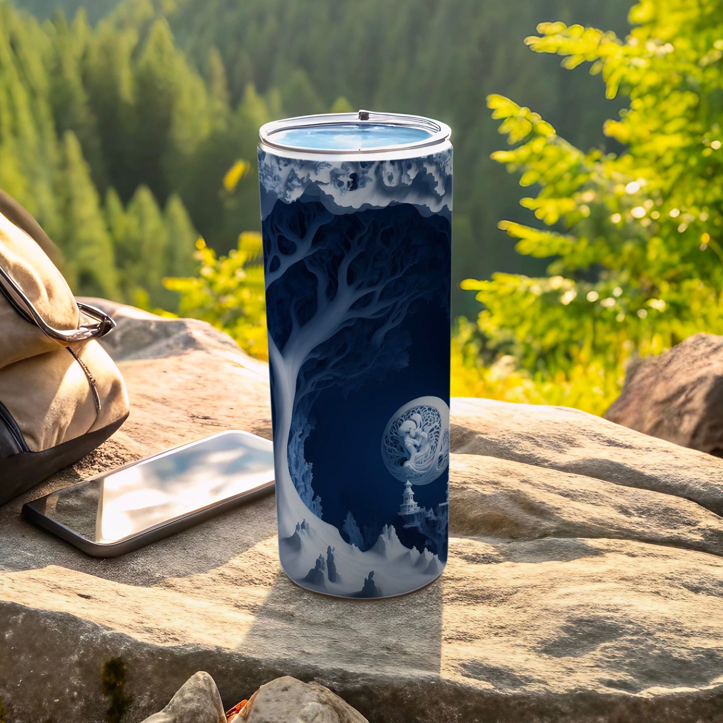Blue fantasy landscape wrap on a tall tumbler, resting on rocks.