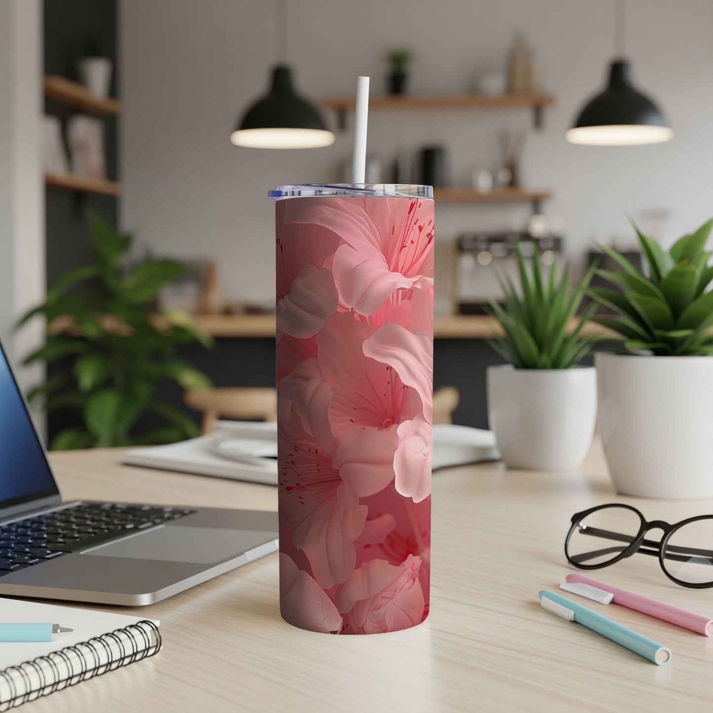 Pink floral tumbler with straw on a wooden desk.