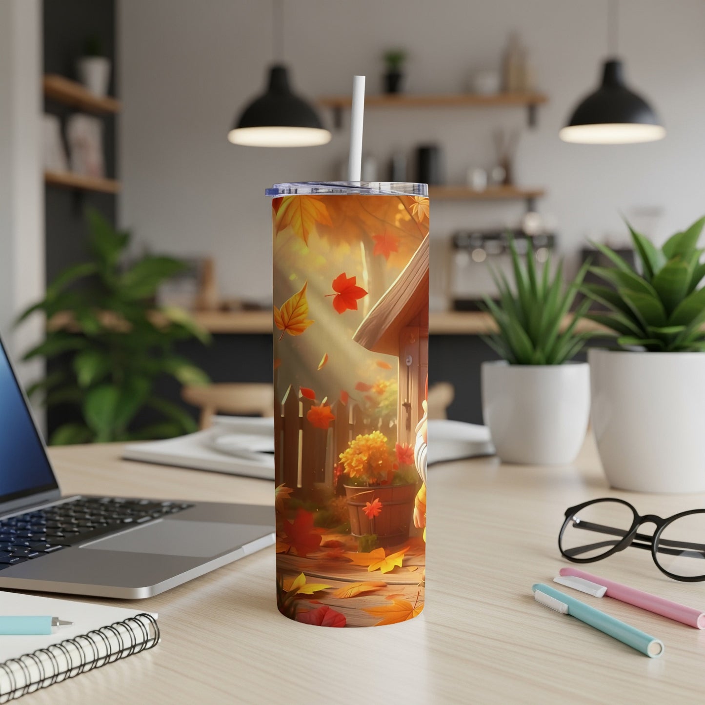 Tumbler with autumn leaves, wooden fence, and pumpkins on a desk.