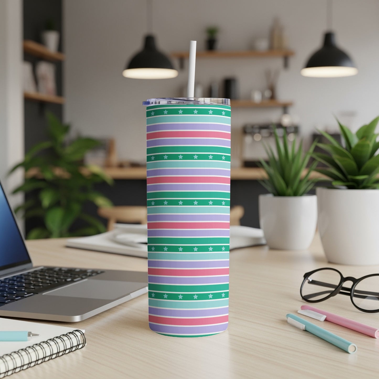 Striped tumbler with stars, white lid, straw, on a desk.