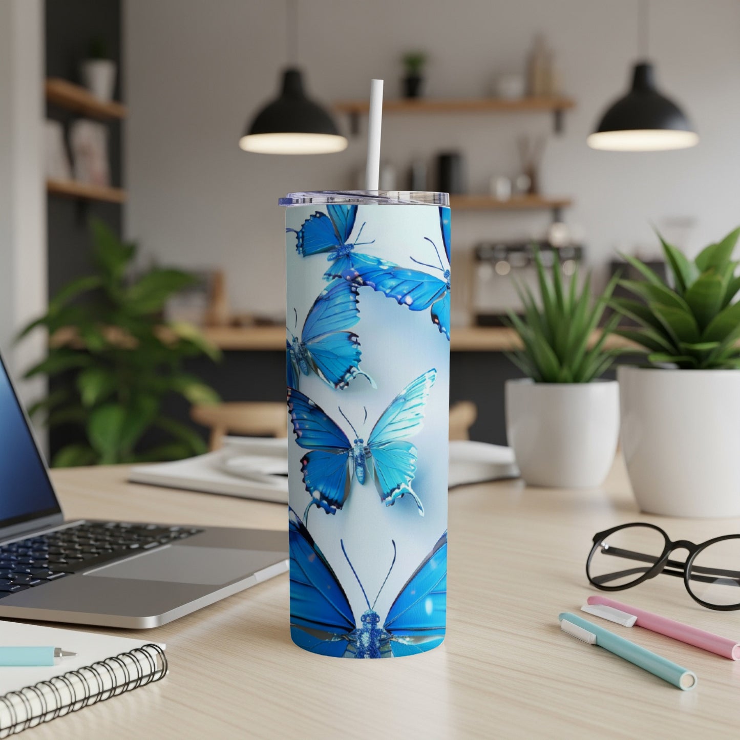 Blue butterflies on a tumbler with a straw, on a desk.