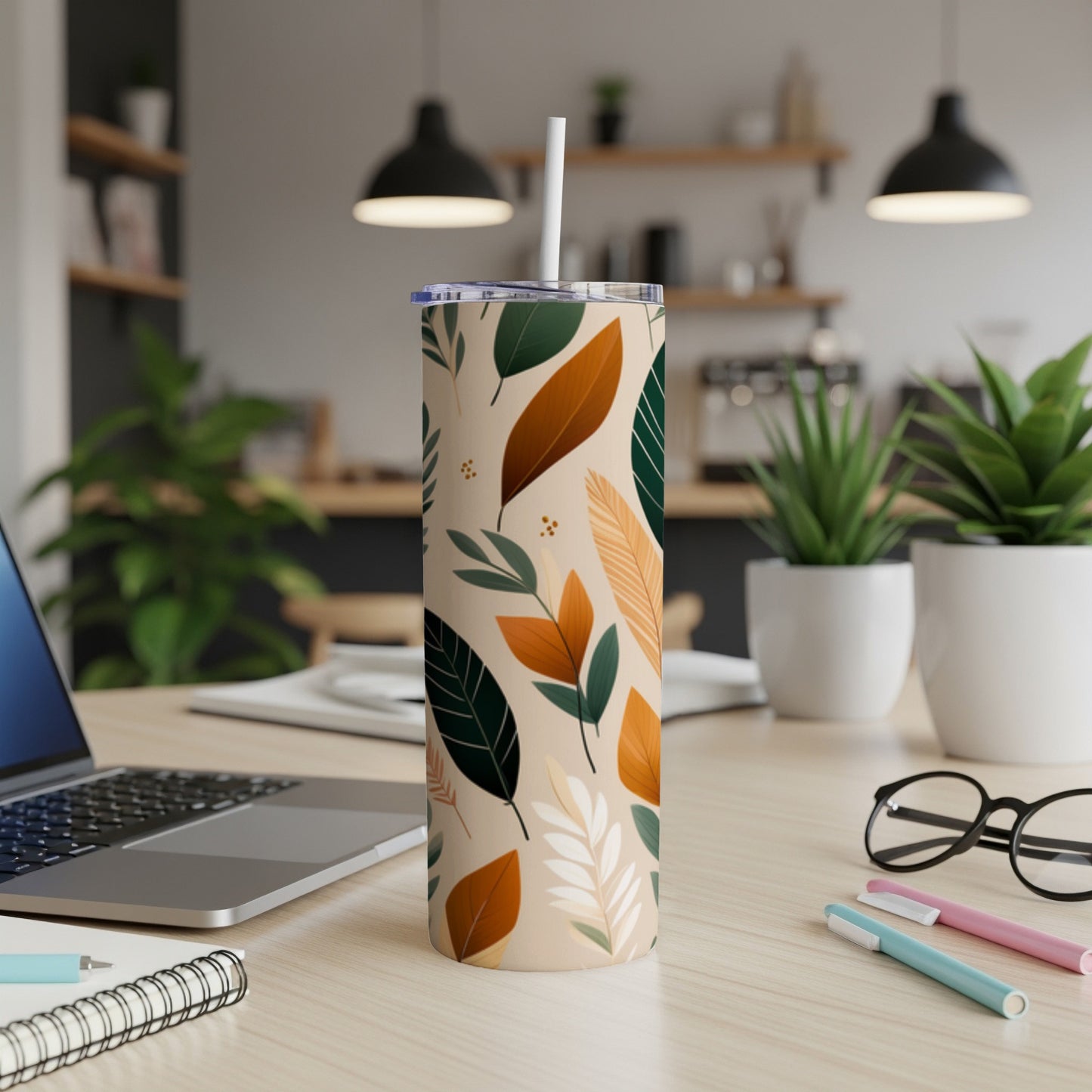 Tall tumbler with abstract leaf pattern, white straw, on a desk.