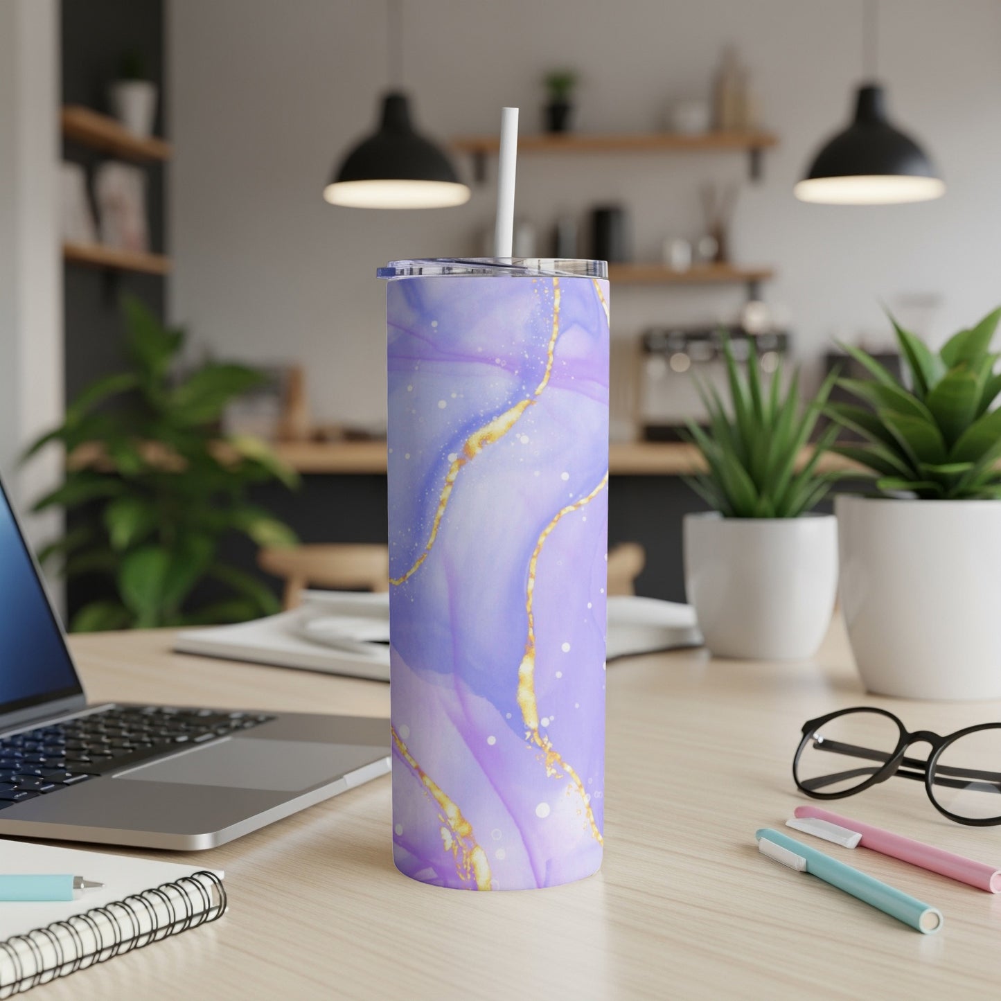 Purple and gold marbled tumbler with white straw on a desk.