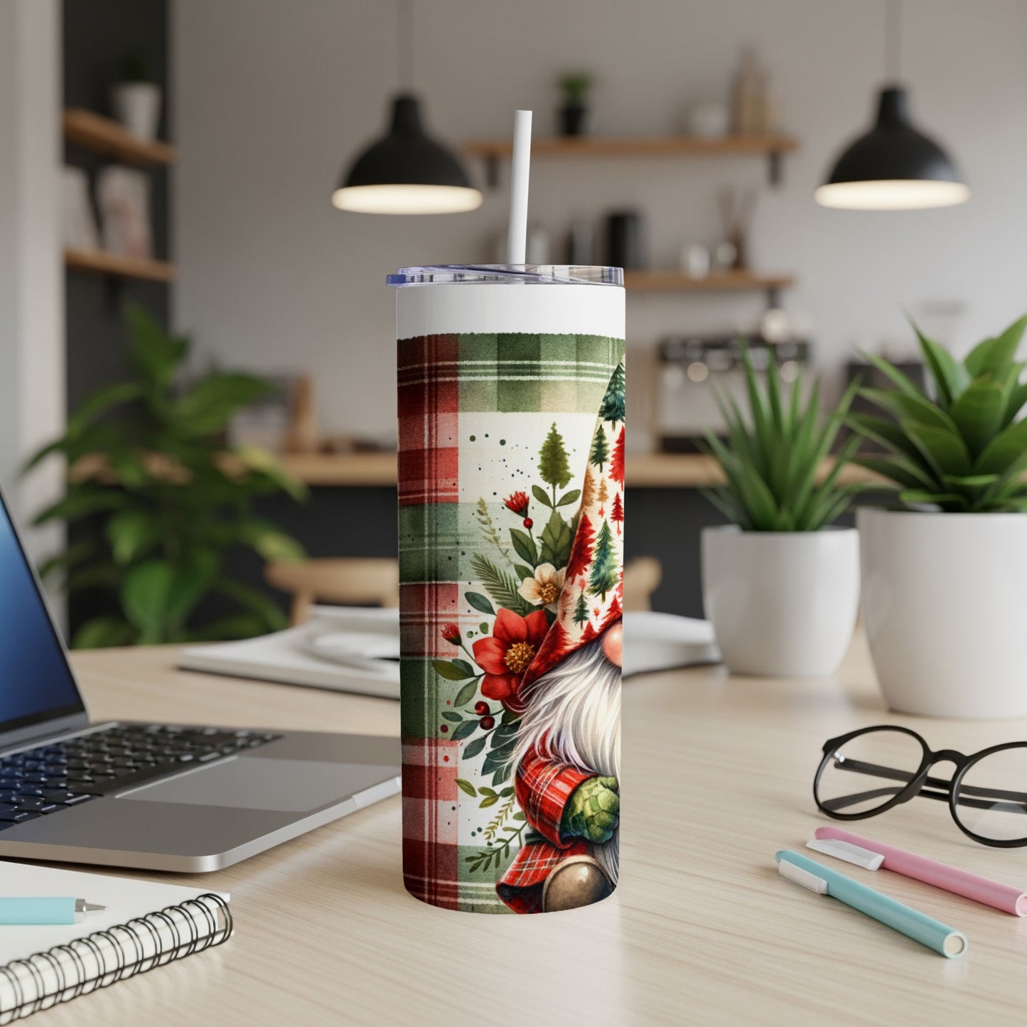 Tall tumbler with Christmas gnome and plaid pattern, on a desk.