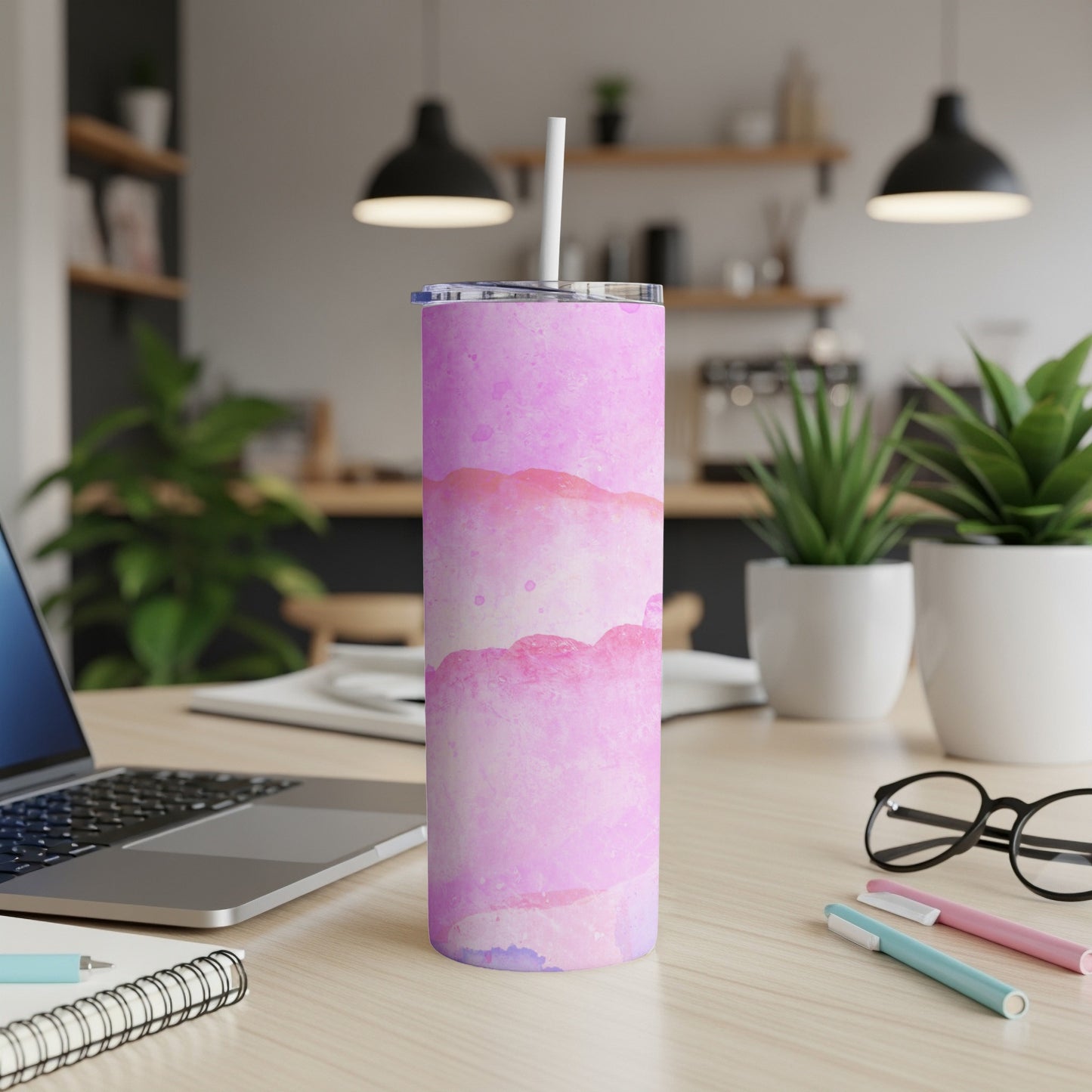 Pink and purple watercolor tumbler with straw on a desk.