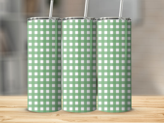 Three green and white checkered tumblers with straws on a wooden surface.
