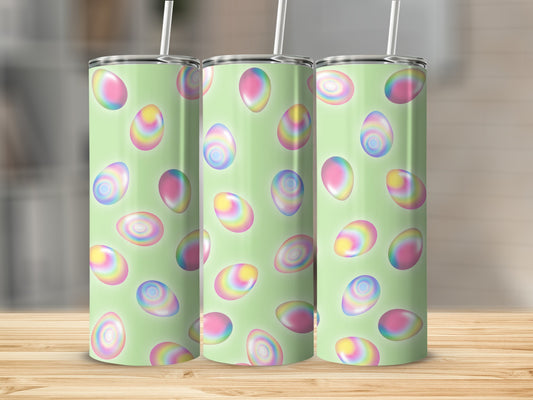 Three pastel Easter eggs on a light green patterned tumbler with straws.