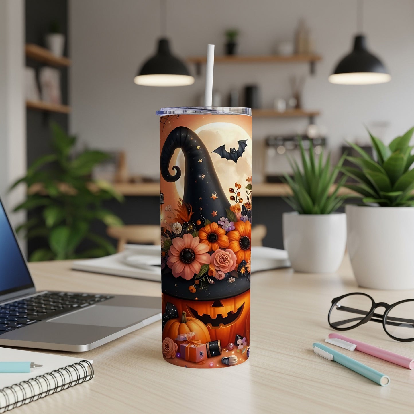Halloween tumbler with witch hat, pumpkins, flowers, and a bat against a full moon.