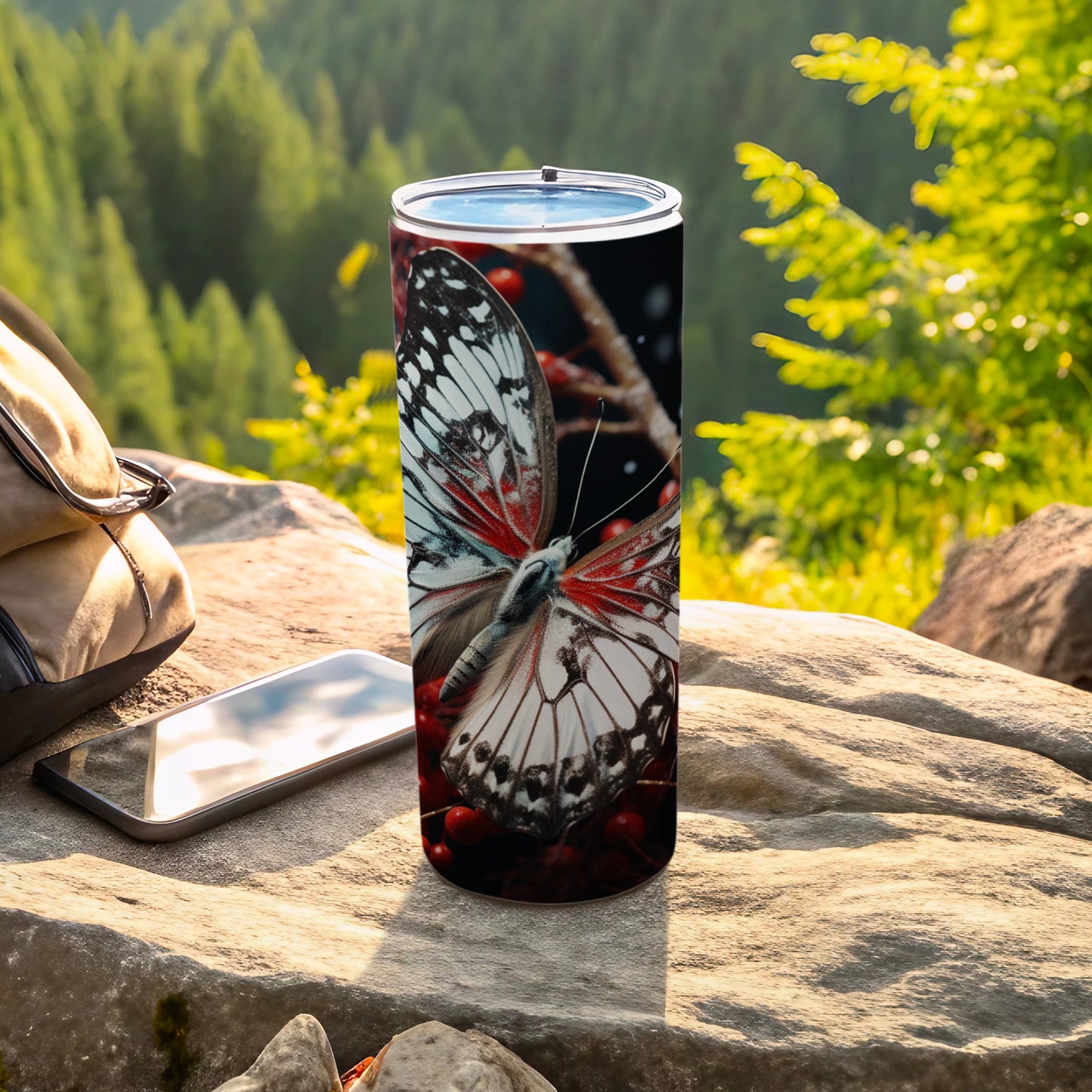 White and red butterfly on a metal tumbler with a blurred forest background.