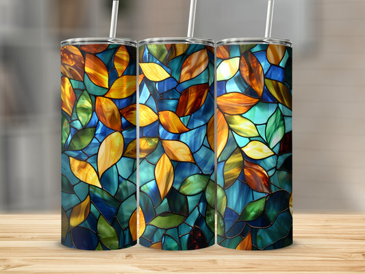 Three stained glass tumblers with colorful leaf patterns on a wooden surface.