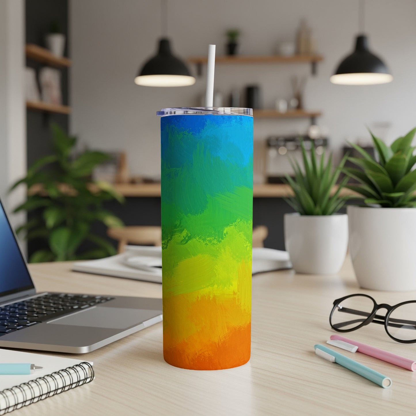 Rainbow gradient skinny tumbler with white straw on a desk.